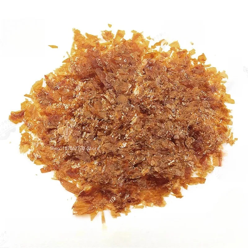 A pile of amber-colored translucent crystalline granules of 50g shellac varnish for primer handmade guitar material