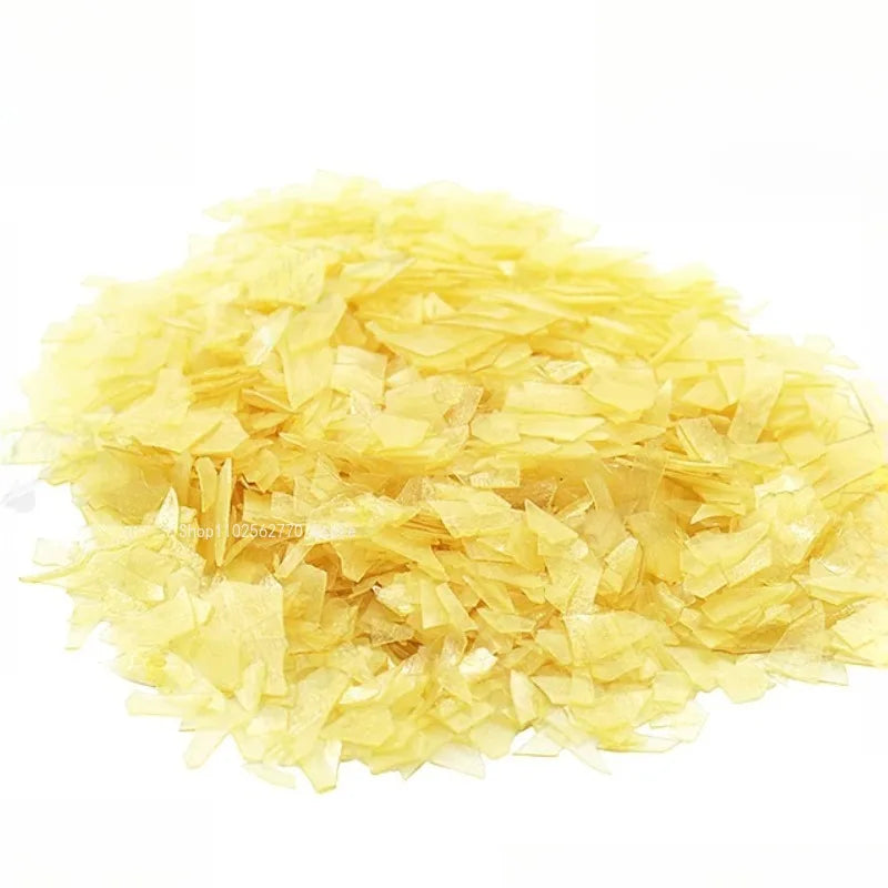 A pile of translucent pale yellow irregular flakes of 50g shellac varnish used as primer handmade guitar material