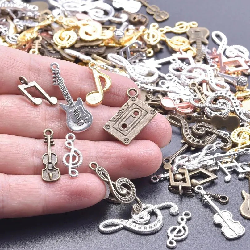 A hand holds vintage random diy bulk violin guitar musical note charms in mixed colors and metal for jewelry making