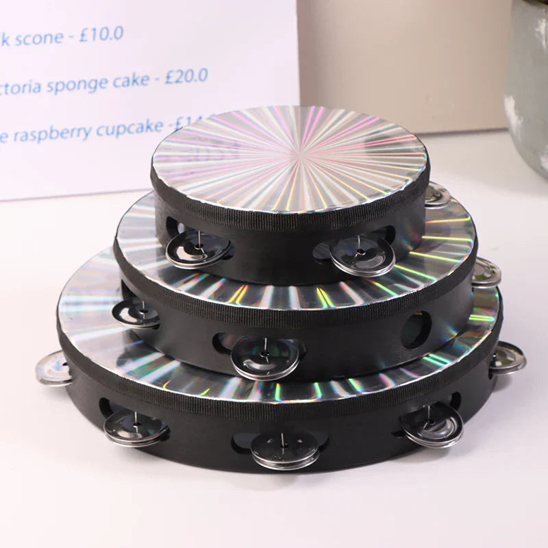 Stacked black wooden radiant tambourine handbells with iridescent sunburst metallic surfaces and silver jingles for jingle musical educational use
