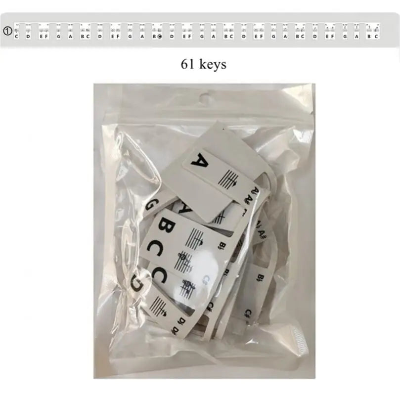 White plastic keyboard note labels with black lettering and silicone strips packaged in clear plastic for piano beginners
