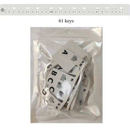 White plastic keyboard note labels with black lettering and silicone strips packaged in clear plastic for piano beginners