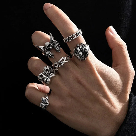 A hand wearing a 7pcs set punk men ring vintage in stainless steel with spider bat skull and two-headed snake motifs