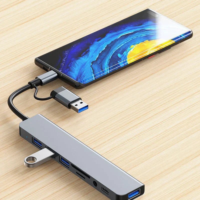 Silver aluminum 8 in 2 usb type c hub with audio jack adapter and card reader laptop connected to smartphone