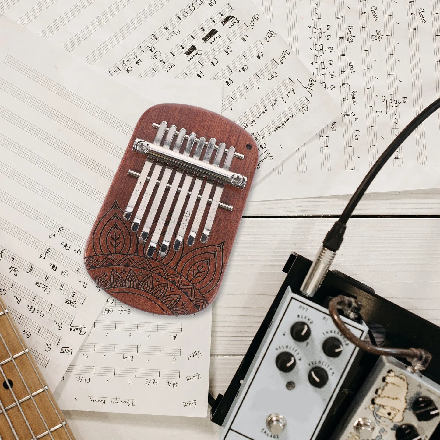 A reddish-brown wooden mini kalimba thumb piano with ten silver tines and leaf engravings for beginners kids adults
