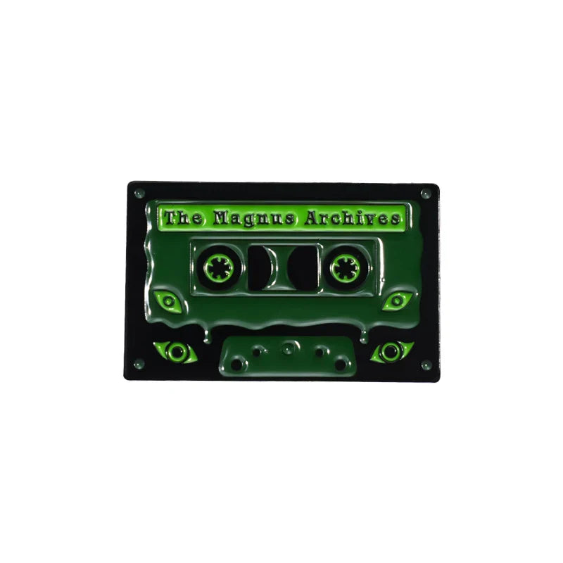 A glossy green enamel pin vintage cassette tape with glowing eyes and the magnus archives label for 90s retro music fans