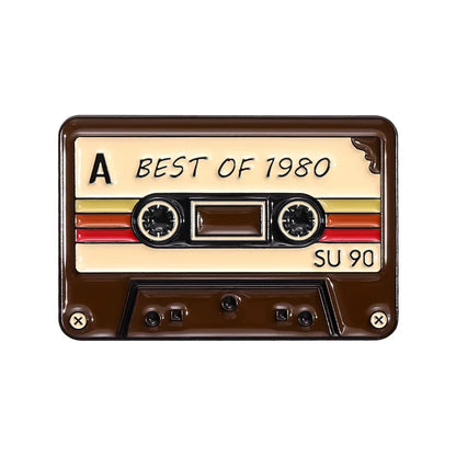 Vintage enamel pin shaped like a cream 80s 90s retro music cassette tape with red yellow stripes and black spools