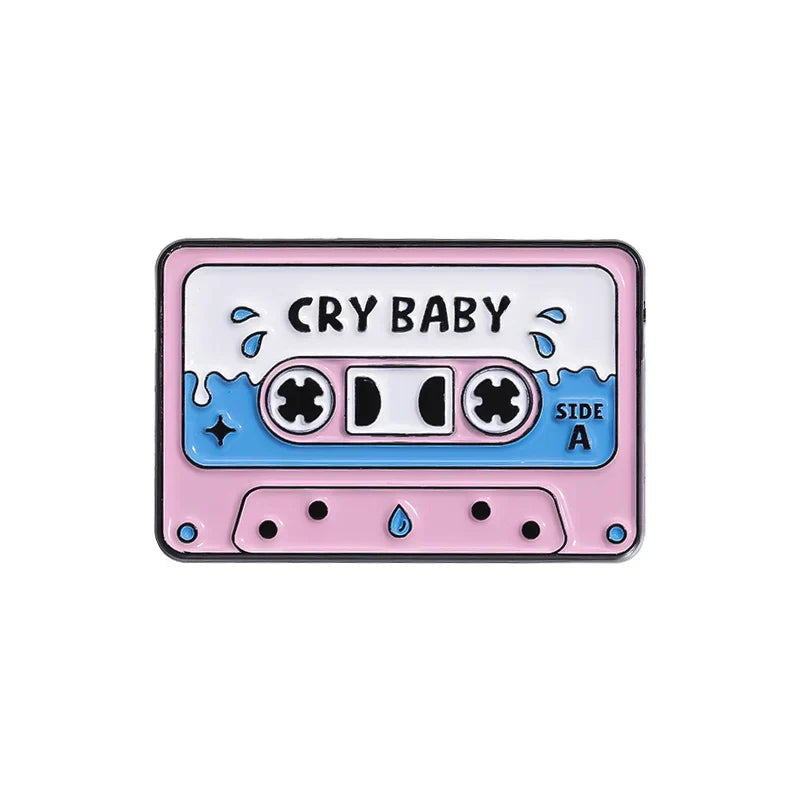 Pink and blue enamel pin shaped like a 90s retro music cassette tape with cry baby print from vintage collection