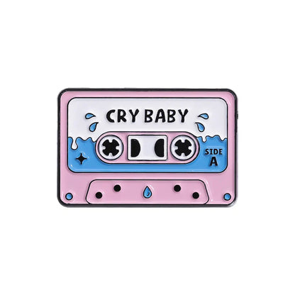 Pink and blue enamel pin shaped like a 90s retro music cassette tape with cry baby print from vintage collection