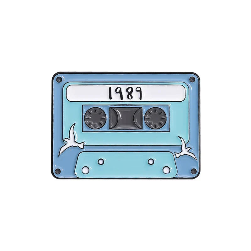 Light blue enamel pin shaped like a 1989 cassette tape with white birds from 90s retro music cassette tape collection