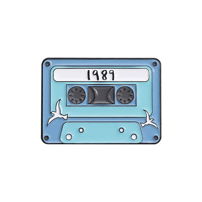 Light blue enamel pin shaped like a 1989 cassette tape with white birds from 90s retro music cassette tape collection