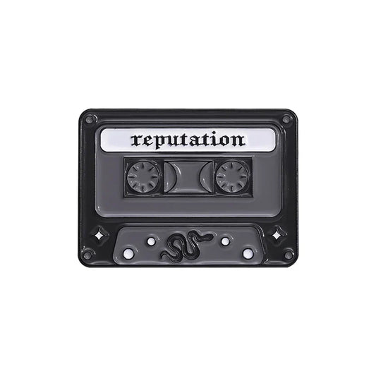 Black enamel pin shaped like a cassette tape with reputation label and snake design from 90s retro music collection