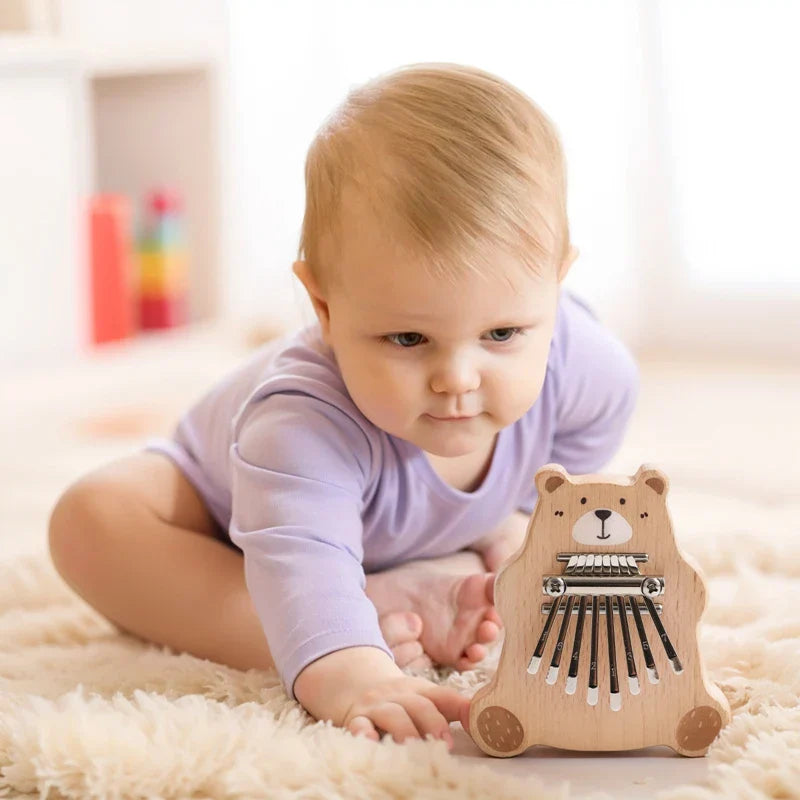A light brown wooden bear thumb piano with black metal keys and white plastic ends portable marimba musical toy for baby montessori toys