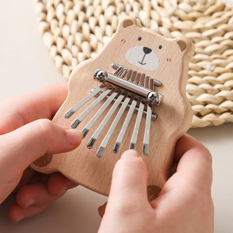 A light wood bear thumb piano with silver metal tines and a smiling face portable marimba musical baby montessori toy