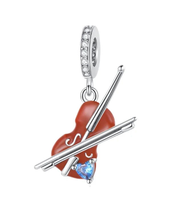 Silver music charm featuring a red enamel piano body crossed with silver drumsticks and a blue heart gemstone for original bangle bracelet