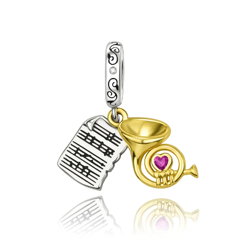Silver and gold sterling silver musical instrument charms featuring sheet music and french horn with pink gemstone heart