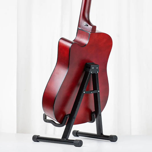 A glossy red acoustic guitar resting on a black metal acoustic guitar stand for electric and upright bass use