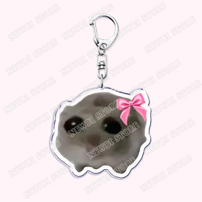 A silver-framed keychain with a gray cratered moon face and pink bow from aesthetic coquette pink womens accessories ribbon collection