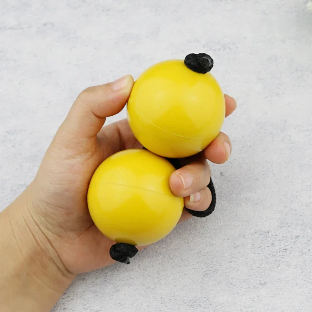 Yellow plastic african shaker kashaka with black rubbery ends used as rhythmic balls for musical percussion