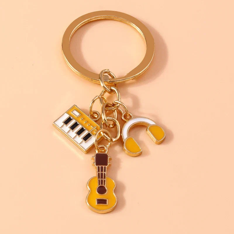 Gold-colored aihua enamel musical instrument keychains featuring keyboard headphones and guitar charms for women girls diy use