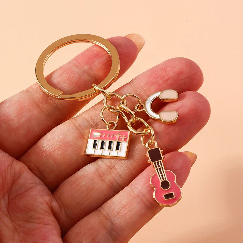 Gold-toned aihua enamel musical instrument keychains with pink and white keyboard guitar and headphone charms for women girls diy