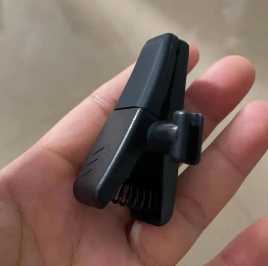 Black plastic musical instrument microphone clip with spring mechanism and textured grip for mic clamps stringed use