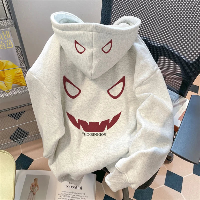 Light gray fleece y2k streetwear hoodie with bold red devil graphic featuring triangular eyes and jagged teeth on a chair
