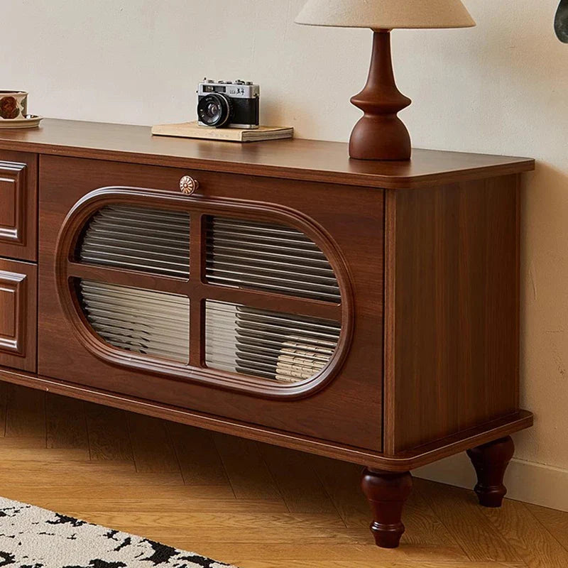 A rich brown wooden vintage tv stand with oval glass-fronted compartment and brass knob in mid century aesthetic cabinet classic luxury