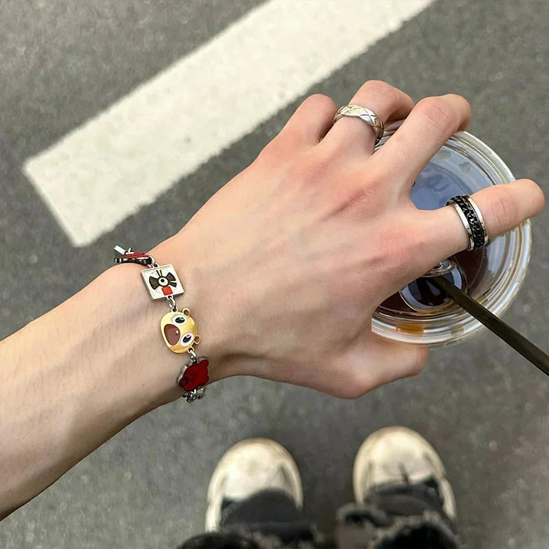 A silver metal cuff bangle featuring a black and white camera pendant yellow kawaii face and red heart charm for vintage style