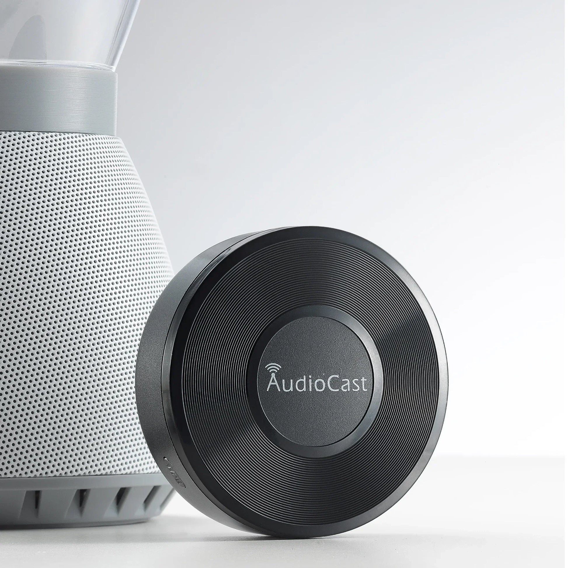 Black circular audiocast m5 music audio streamer with textured ribbed surface and silver logo for airplay audio music use
