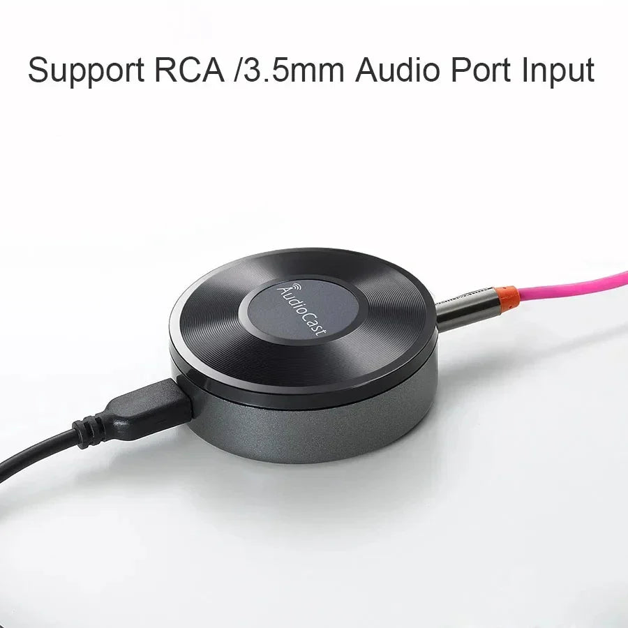 Black circular audiocast m5 wireless wifi music audio streamer with rca and 3.5mm ports connected to pink and black cables