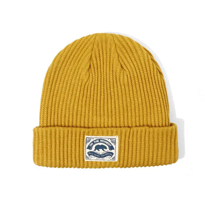 A mustard-yellow ribbed knit beanie with a folded cuff and bear patch ideal for women hip hop punk crochet bonnet style
