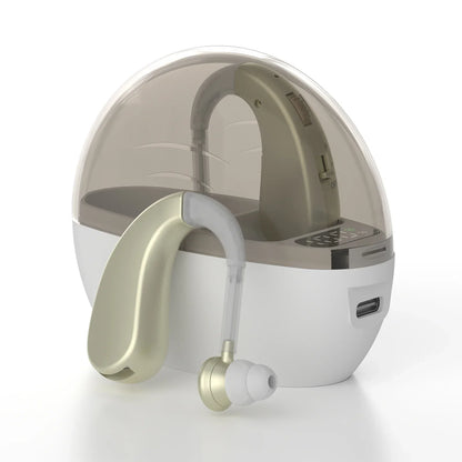 Gold-colored behind-the-ear headphones sound amplifier with noise reduction and adjustable volume beside white charging case