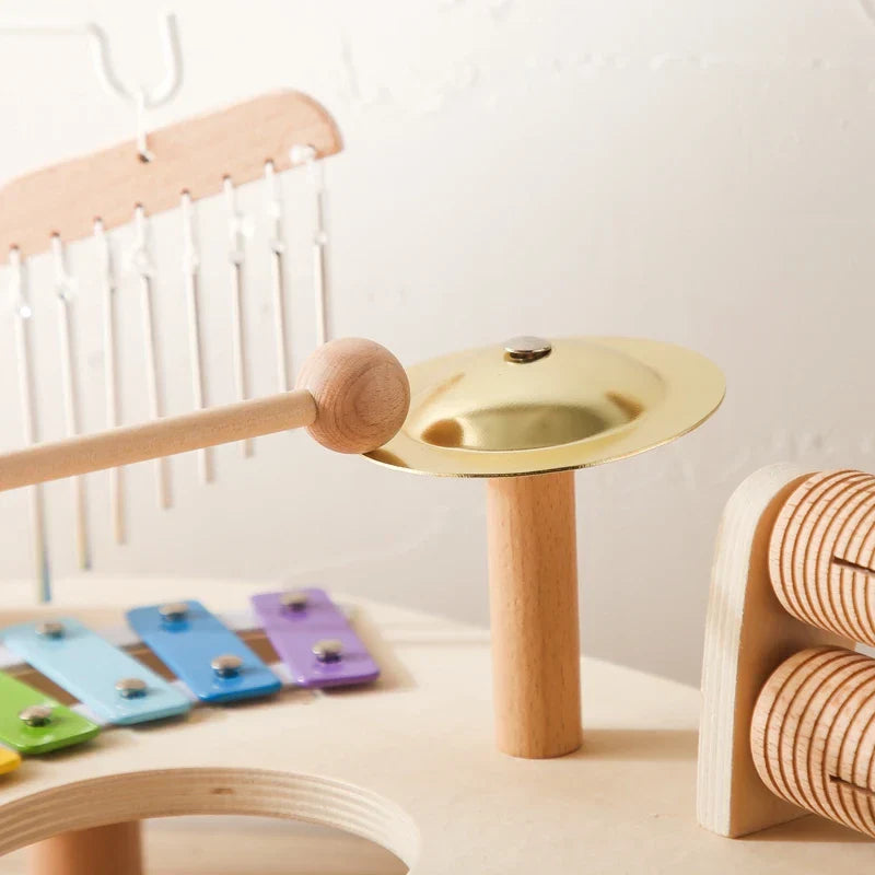 A golden brass aeolian bell with wooden handle and base among colorful wooden musical toys xylophone for baby educational toys