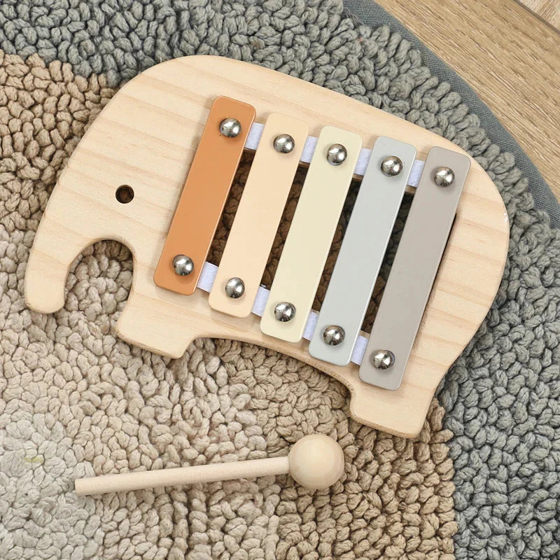 A wooden baby montessori toy cartoon elephant percussion xylophone with five pastel keys and a matching mallet