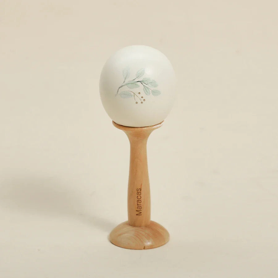 White ceramic baby musical toy maraca with light green leaf design on natural wood stand for educational instrument playthings