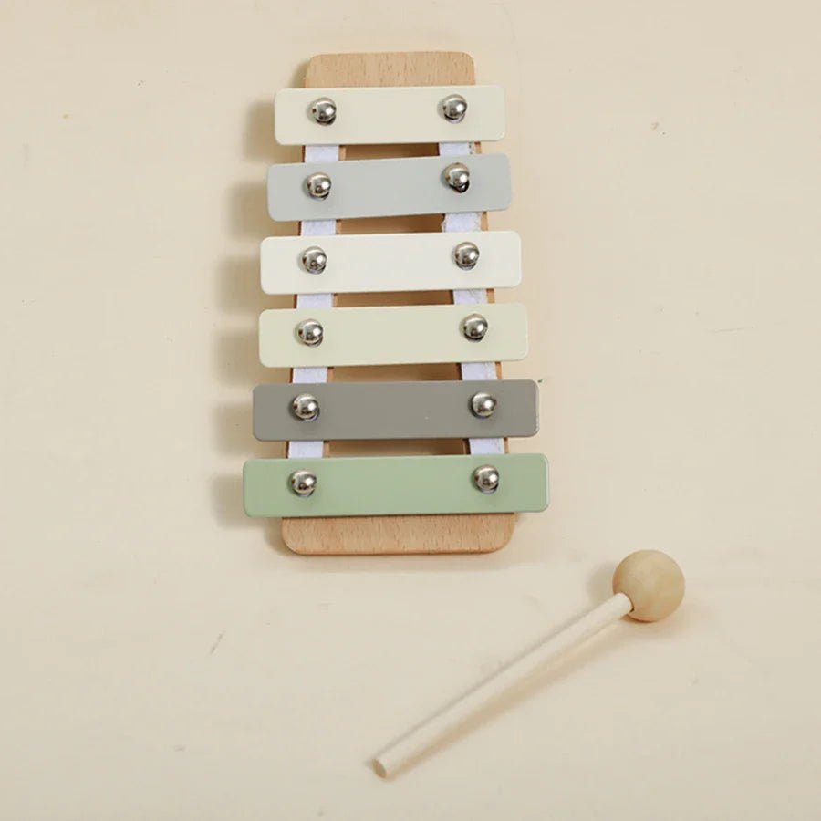 A wooden children’s xylophone with six pastel keys in white gray and mint green for baby musical toys and educational playthings
