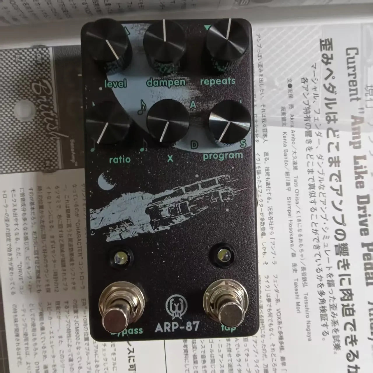 Black arp-87 guitar pedal with silver knobs and white spaceship graphic for timing speed measurement in delay effects