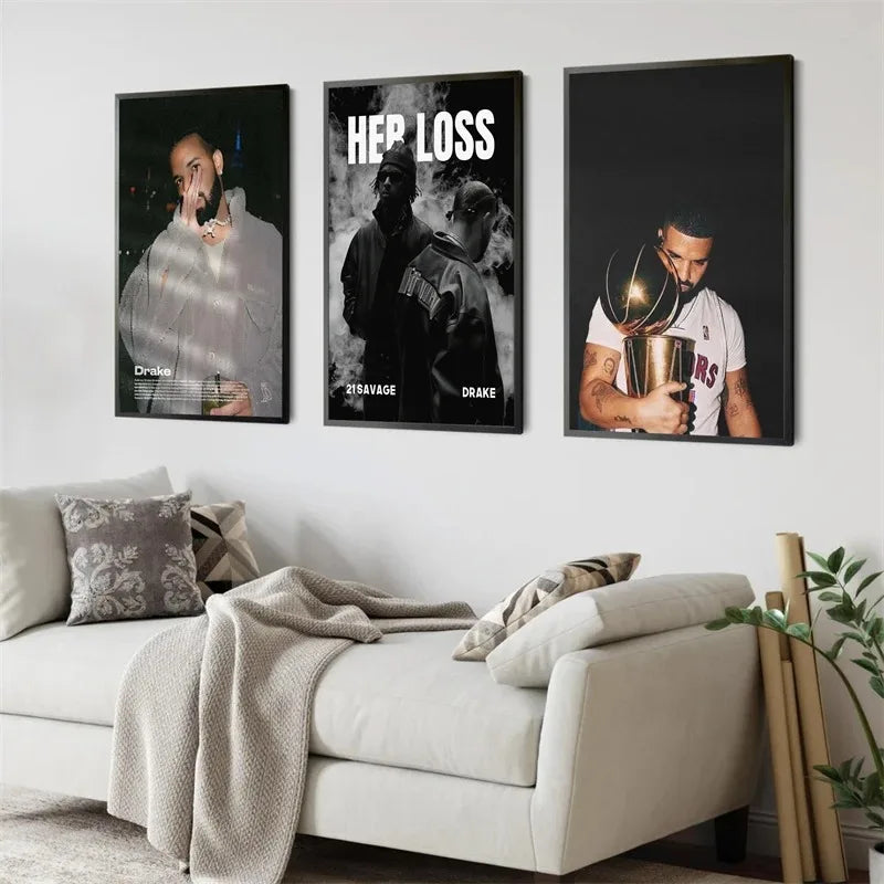 Three framed black and white and color posters featuring drake 21 savage and basketball trophy scene above white sofa wall art