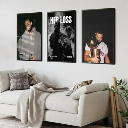 Three framed black and white and color posters featuring drake 21 savage and basketball trophy scene above white sofa wall art