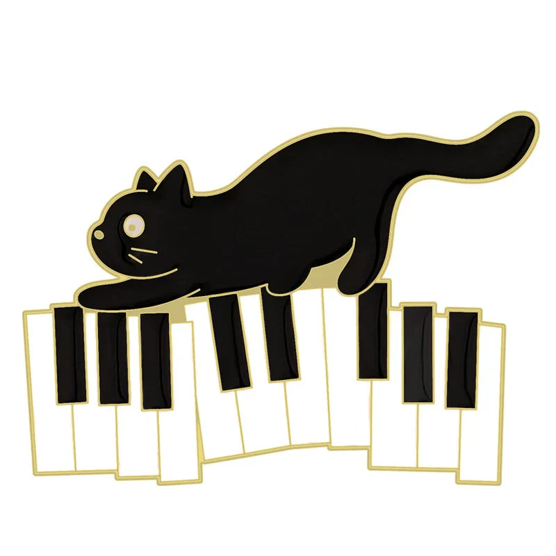 Black cat music enamel pin shaped like an animal cute musical piano brooch badge resting on gold-trimmed piano keys