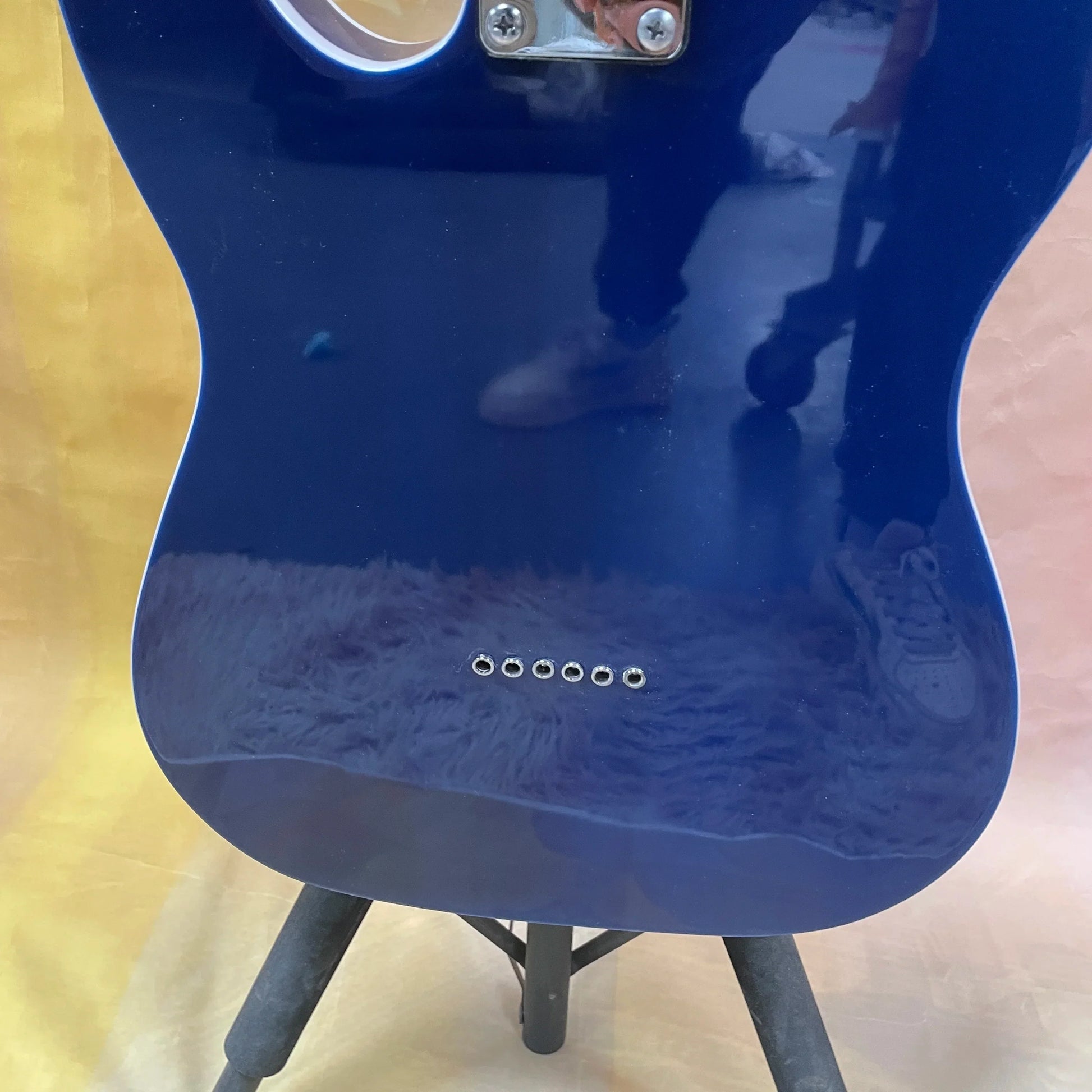A glossy blue tl electric guitar body with white binding, rosewood fingerboard, and six silver tuning pegs