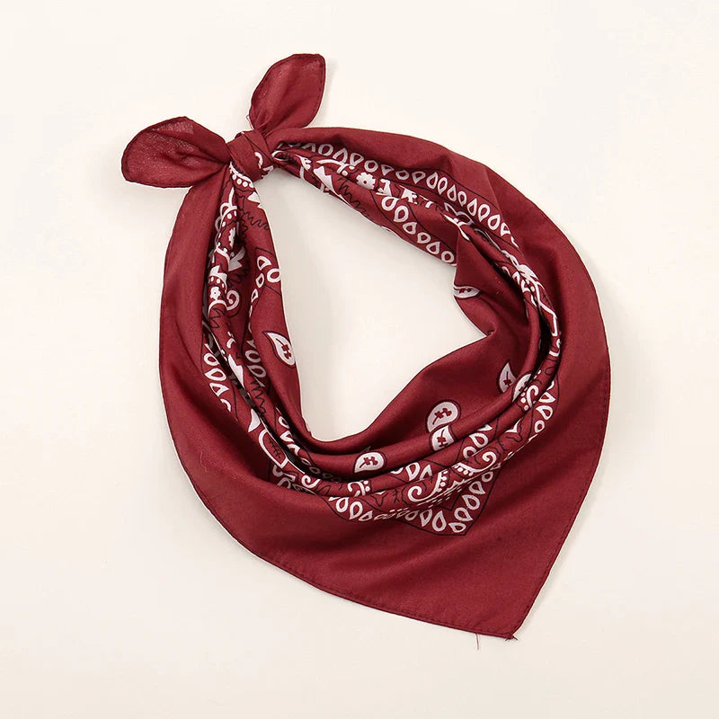 A maroon bohemian print bandana with white paisley pattern tied in a knot for printed headbands hiphop and wrist wraps face