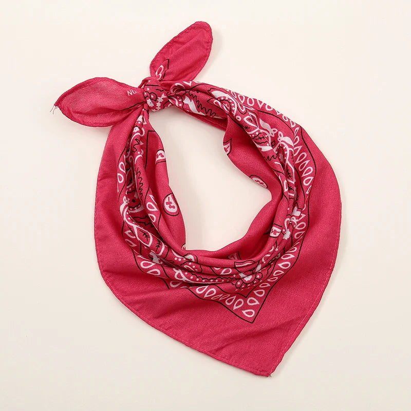 A vibrant pink bohemian print bandana with white paisley pattern tied as a printed headbands hiphop wrist wraps face mask
