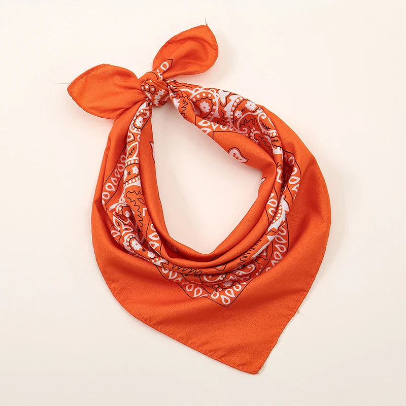 Vibrant orange bohemian print bandana with white paisley pattern tied in a neat knot for printed headbands hiphop wrist wraps face use