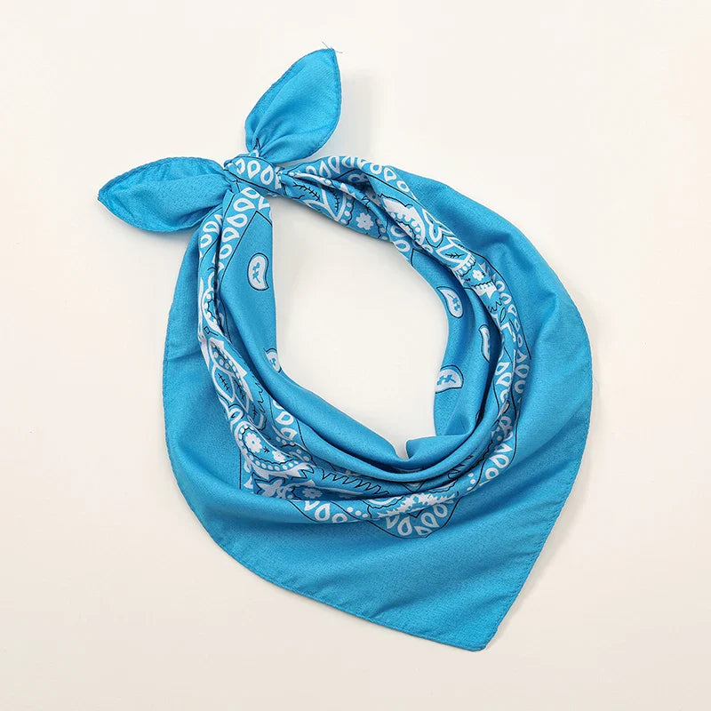 A vibrant blue bohemian print bandana with a white paisley pattern tied in a knot for printed headbands hiphop use