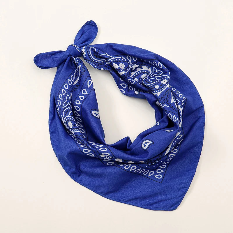 A vibrant royal blue bohemian print bandana with white paisley pattern tied in a neat knot for printed headbands hiphop