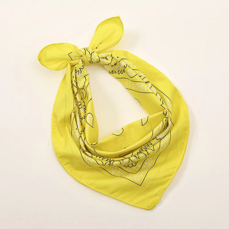 Bright yellow bohemian print bandana with black skull and crossbones pattern tied as a printed headbands hiphop wrist wraps face accessory