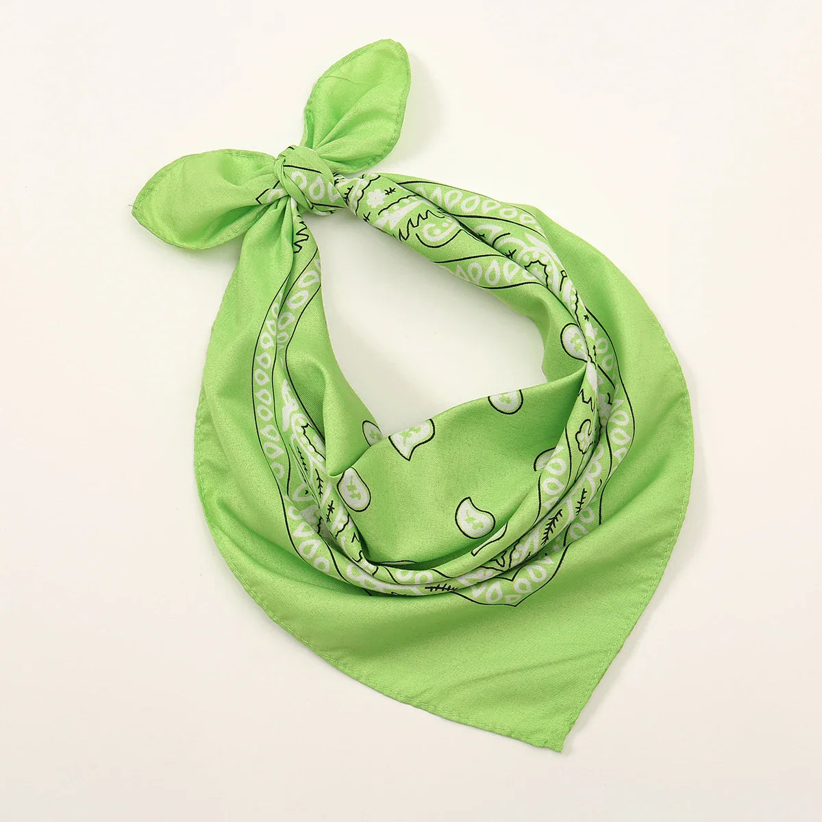 A vibrant lime green bohemian print bandana with a white and black paisley pattern tied as a printed headbands hiphop wrap