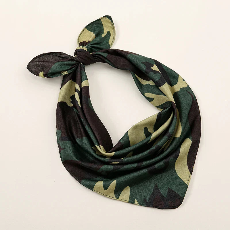 A soft satin-like bohemian print bandana in olive green and dark brown camouflage tied into a knot for wrist wraps face use